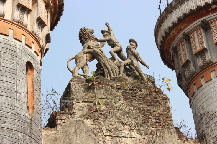 Figures atop the gate showing two sahibs fighting a lion |  Photograph by  Calcutta কাহিনী at Dhanyakuria